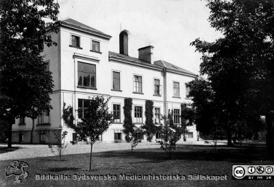 Länssjukhuset i Ystad.
Länssjukhuset i Ystad. Fasad mot väster på en flygel. Foto troligen före mitten på 1920-talet samtidigt med bilden i fil 210924BE-006. Bildkälla Denise Andersson 2021. Ur  hennes mans farfars efterlämnade bilder. Denne var Charly Urbanus Andersson, 18920525-3918, född i Ljunits, Sjörups församling vid Ystad, död 1974-02-14 och då kyrkobokförd på S Vallösa 5, 27012 Rydsgård. Han var  skräddare och fotograf, bosatt i Vallösa utanför Ystad. Fotografens mor skall ha tillbringat sina sista år här som mycket gammal.
Nyckelord: Skräddare;Fotograf;Länslasarett;Flygelbyggnad.