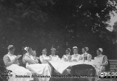 Kaffepaus i en sjukhuspark. 
Bild 20 i husmor Anna Landelius (1880-1964) efterlämnade fotoalbum. Ingrid Frennhoff (f. 1944) hade övertagit detta album efter sin morfar som i sin tur tagit hand om det efter sin syster husmor Anna på Lasarettet i Lund. Gåva till Sydsvenska Medicinhistoriska Sällskapet nyåret 2020.- Många av sjuksköterskorna bär SSSH-uniform med mössa, brosch och hakband.
Nyckelord: Sjukhuspark;SSSH;Södra Sveriges Sjukköterskehem;Kaffepaus