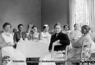 Kaffepaus med patienter och sköterskor.
Bild 46 i husmor Anna Landelius (1880-1964) efterlämnade fotoalbum. Ingrid Frennhoff (f. 1944) hade övertagit detta album efter sin morfar som i sin tur tagit hand om det efter sin syster husmor Anna på Lasarettet i Lund. Detta album är en gåva från Ingrid Frennhoff till Sydsvenska Medicinhistoriska Sällskapet nyåret 2020.

Nyckelord: Sköterskor;Sköterskeelever;Patienter;Paus;Kaffepaus