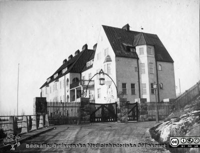 Kanske ett sanatorium
Bild 63 i husmor Anna Landelius (1880-1964) efterlämnade fotoalbum. Ingrid Frennhoff (f. 1944) hade övertagit detta album efter sin morfar som i sin tur tagit hand om det efter sin syster husmor Anna på Lasarettet i Lund. Detta album är en gåva från Ingrid Frennhoff till Sydsvenska Medicinhistoriska Sällskapet nyåret 2020.

Bilden visar en stor byggnad, men knappast Orupssjukhuset som Anna Landelius var husmor på under en tid nära 1920. Tillgängliga bilder visar en annorlunda fasad på Orupssjuhuset och ett läge i skog.
Nyckelord: Sjukhus