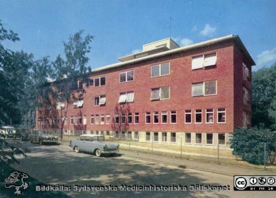 Universitetssjukhuset i Lund, norra området
Lasaettet i  Lund. Reumatiska klinikens tillbyggnad från 1954-57. Efter tryckt vykort. Lasarettskiosken Allan Wahlström, Lund. Foto före september1967 då högertrafik infördes. Efter samma vykort som bild SMHS2680.
Nyckelord: Lasarettet;Lund;Reumatologisk;Klinik;Vykort