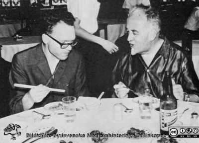 Erik Ask-Upmark (till höger i bilden) på restaurang i HongKong tillsammans med Hans Olov Sjögren, senare professor i Lund. 
Foto rimligen ungefär 1960. Från Ask-Us autobiografi 1969.
Nyckelord: Medicinsk fakultet;Medicinska fakulteten i Lund;Medicinska kliniken i Uppsala;Restaurangbesök;Kongressbesök