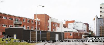 Universitetssjukhuset SUS Lund, mars 2012. 
Vy västerut längs Klinikgatan vid ögonkliniken A och akutmottagningen.Kvinnokliniken mellan dessa båda. Den trista mörka lådan hitom ögonkliniken är en distributionscentral för medicinska gaser.
Nyckelord: _Ögonklinik;KK;Kvinnoklinik;BB;Förlossningsavdelning;Akutmottagning;Centralblocket;Lund;Universitetssjukhuset;USiL