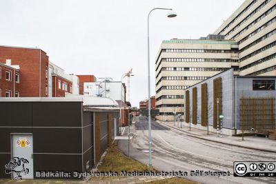 Universitetssjukhuset SUS Lund, 2012. Klinikgatan vid ögonkliniken A och akutmottagningen.
Universitetssjukhuset SUS Lund, mars 2012. Vy västerut längs Klinikgatan vid ögonkliniken A och akutmottagningen.Kvinnokliniken mellan dessa båda med en hisklig baracklåda med brandstege på sin nordöstra flygel. Den trista mörka lådan hitom ögonkliniken är en distributionscentral för medicinska gaser.
Nyckelord: _Ögonklinik;KK;Kvinnoklinik;BB;Förlossningsavdelning;Akutmottagning;Centralblocket;Lund;Universitetssjukhuset;USiL