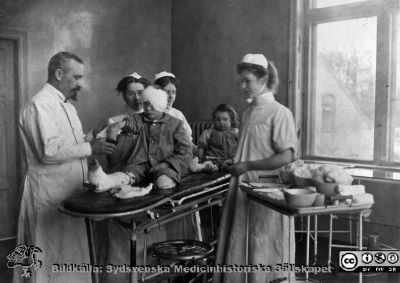 Ängelholms sjukhus. Omläggning av förband på barn.
Ängelholms sjukhus. Omläggning av förband på barn. Läkaren kan vara dr Carl Adlercreutz. Foto rimligen under 1900-talets första halva. Bildkälla: Lillie Börjessons bildsamling från Ängelholms sjukhus.
Nyckelord: Engelholm;Ängelholm;Sjukhus;Operationsbild