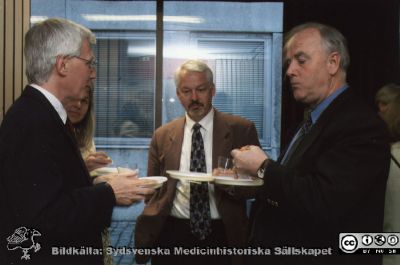 Ortopediska kliniken i Lund 2000.Vårdadministratören Berit Jakobsson avtackas i sjukhusaulan.
Från ortoped klin album 01, Lund. Fotograf Berit Jakobsson. 2001. Mingel utanför sjukhusets aula. Docent (senare professor) Gunnar Hägglund, docent (senare professor) K.-G. Thorngren, professor Lars Lidgren i samkväm i sjukhusaulans nedre foajé i samband med framförandet av  Henning Mankells monolog "Grävskopan" med Tommy Borgström från Ystads Stående Teatersällskap, specialskriven för honom. Föreställningen gavs  inför klinikens personal som avtackningspresent till klinikföreståndaren och vårdadministratören Berit Jakobssonl.
Nyckelord: Lund;Universitetssjukhus;USiL;Kliniker;Ortopedi;Personal;Läkare