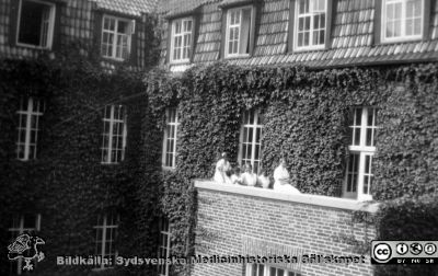 Sjuksköterskor på en balkong på  röntgenavdelningens dåvarande östra fasad på lasarettet i Lund.
Foto troligen på 1930-talet innan huset breddades österut så att balkongen försvann. Från Syster Elinas fotoalbum (Elina Holmberg?).
Nyckelord: Röntgen;Lasarettet i Lund