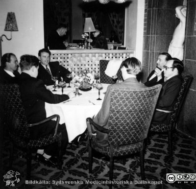 Sex herrar runt ett restaurangbord. 
Den bortre är Martin Lindgren som disputerade 1958. Kanske firade de detta?
Nyckelord: Restaurant;Fest;Disputation;Lunds universitet