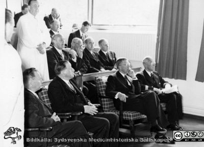 Kung Gustaf VI Adolf på besök på radiologiska kliniken i Lund 1951 då den s.k. koboltkanonen demonstrerades för honom och kanske invigdes. Doc. Gunnar Gorton står i vit läkarrock i bildens övre vänstra hörn. Två icke identifierade landstingspolitiker sitter längst till vänster på första stolsraden. På bild SMHS0562 står klinikchefen Bertil Ebenius i talarstolen inför samma åhörare.
Nyckelord: Radiologisk;Onkologisk;Klinik;Lasarettet i Lund;Medicinska fakulteten;Universitetet i Lund;Föreläsning