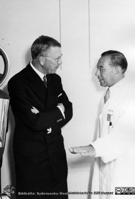 Kung Gustaf VI Adolf besöker radiologiska kliniken i Lund 1951 
Kungen skulle bese och kanske inviga Kurt Lidens s.k. koboltkanon. Här ses han vid apparaten, intresserat lyssnande på klinikchefen Bertil Ebenius när denne berättar om koboltkanonen och dess värde för cancerbehandling. Från Syster Elinas fotoalbum (Elina Holmberg?).
Nyckelord: Onkologisk;Radiologisk;Jubileumsklinik;Lasarettet i Lund;Medicinska fakulteten;Invigning