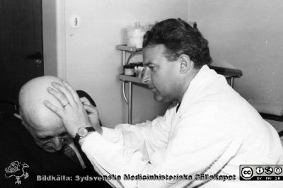 Dr Martin Lindgren (senare professor i radiologi i Lund) undersöker en patient.
 Foto troligen på 1950-talet. Från Syster Elinas fotoalbum (Elina Holmberg?) .
Nyckelord: Onkologisk;Radiologisk;Jubileumsklinik;Undersökning;Patient