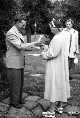 Radiologer besöker docent Bertil Ebenius i Blekinge skärgård.
Radiologer besöker docent Bertil Ebenius (1902-1959) och hans hustru Dagmar (1904 - 1999) på deras ö Stickelön utanför Bökevik i Blekinge, bredvid den större ön Saltärna. Rimligen uppvaktning på någon bemärkelsedag. Rimligen på Bertil Ebenius 50-årsdag den 18/8 1952? Kvinna med manuskript i handen överräcker en statyett som gåva till docent Bertil Ebenius. Från Syster Elinas fotoalbum (Elina Holmberg?).
Nyckelord: Uppvaktning;Radiologisk;Klinik;Lunds universitet;Blekinge skärgård