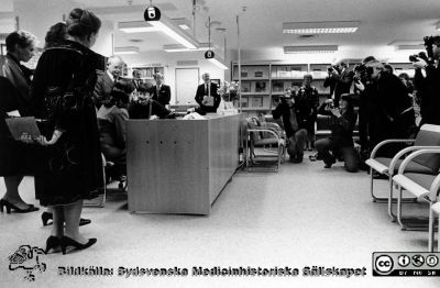 Drottning Silvia  på sjukhusbiblioteket på Lasarettet i Lund 
Lasarettsfotograferna i Lund,  pärm  Sv/v Neg, 83:2. Drottning Silvia  besöker Lasarettet i Lund i samband med Forskningens Dag. Här är hon på sjukhusbiblioteket omgiven av administrativa chefer på sjukhuset (bl.a. professor Hans Rorsman) och uppvaktad av en skara fotografer. 83-11-10. A17. Från foto.
Nyckelord: Lasarettet;Lund;Universitetssjukhuset;USiL;Silvia;Drottning;Fotografer;Sjukhusbiblioteket;Forskningens Dag