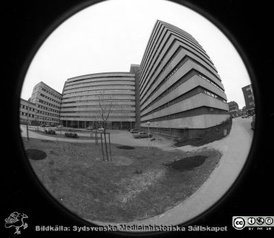 Centralblocket i Lund med nytt objektiv
Lasarettsfotograferna i Lund,  pärm  Sv/v Negativ, 1985. 31/85. Centralblocket på Lasarettet i Lund provfotograferat med fotoavdelningens nya fina supervidvikelobjekti, typ "Fisheye". Vy av byggnadens fasad mot väster med huvudentrén. Till vänster AB-blocket, till höger onkologiska kliniken och kvinnokliniken. Från negativ
Nyckelord: Lasarettet;Lund;Universitetssjukhuset;USiL;Centralblocket;Entr