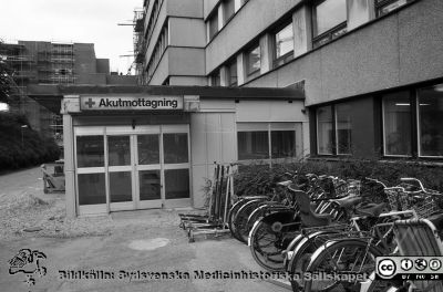Entrén, akutmottagningen i Lund 1985
Lasarettsfotograferna i Lund,  pärm  Sv/v Negativ, 1985. 85/47. Entrén till dåvarande akutmottagningen på AB-blockets norrsida, under ombyggnad och med cykelställ. F-blocket under byggnad i bakgrunden. Från negativ
Nyckelord: Lasarettet;Lund;Universitetssjukhuset;USiL;Enr;Cykelställ;CentralbBlocket