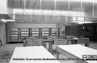 Nya centralköket, troligen 1960
Lasarettsfotograferna i Lund,  pärm,  96+97 (?). 14. Köket. Nya centralköket, färdigt i första etappen 1960 och den andra 1964. Beredningsbord, Stekbord, ugnar och värmeskåp. Foto troligen från 1960. Kanske reprofoto. Från negativ
Nyckelord: Lasarettet;Lund;Universitetssjukhuset;USiL;Centralkök