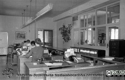 Expeditionsdisk på gamla sjukhuskontoret
Lasarettsfotograferna i Lund,  pärm,  96+97 (?). 14. Expeditionsdisk på gamla kontoret vid Allhelgona Kyrkogata. Löneutbetalningar och många andra personalärenden sköttes här, över disk. Foto troligen 1960 då nya administrationsbyggnaden vid Getingevägen stod klar. Kanske reprofoto. Från negativ
Nyckelord: Lasarettet;Lund;Universitetssjukhuset;USiL;Administration;Kontor