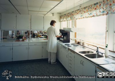 Modellprojektet "Vårdavdelning 2000"
Köks- och serveringsutrymme på "Vårdavdelning 2000", en modellavdelning för 2000-talets kommande ombyggnader i Blocket i Lund, utformad 1988 - 1990 under ledning av Elwy Ekman. Det är Elwy själv som står vid kaffemaskinen.
Nyckelord: Lasarettet;Lund;Universitetssjukhuset;USiL;Vårdavdelning 2000;Serveringskök;Kafferum