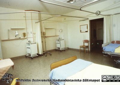 Modellprojektet "Vårdavdelning 2000"
Detta var en modellavdelning inför 2000-talets renoveringar av avdelningar i Blocket i Lund, utformad 1988 - 1990 under ledning av Elwy Ekman. Vårdrum 4, en 4  bäddars vårdsal. Notera skenorna i taket för avskärmningsgardiner. Två sängutrymmen är tomma. Foto 1988-1990. 
Nyckelord: Lasarettet;Lund;Universitetssjukhuset;USiL;Vårdavdelning 2000;Vårdrum