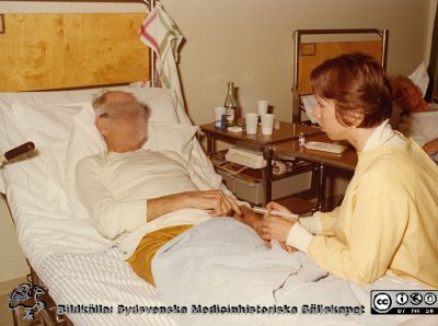 En sängliggande patient får en injektion av en sjuksköterska i gul skyddsrock, infektionskliniken i Lund
Foto ur album tillägnat professor Karl Emil Thulin på hans 60-årsdag, 1975.  
Nyckelord: Lasarettet;Lund;Universitetssjukhuset;USiL;Infektion;Epidemiologiska;Kliniken