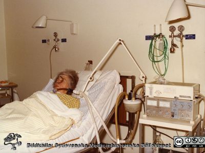 Kvinnlig tracheostomerad patient i en SevoVentilator på infektionskliniken i Lund avd. 80, ~1975
Foto ur album tillägnat professor Karl Emil Thulin på hans 60-årsdag, 1975. Kvinnlig tracheostomerad patient i ventilator, en SevoVentilator, då en alldeles ny och revolutionerande apparat, utvecklad i Lund av Björn Jonson och Lars Nordström. Patienten har också en sond i näsan, kanske för nutriering.
Nyckelord: Lasarettet;Lund;Universitetssjukhuset;USiL;Infektion;Kliniken;Epidemiologiska;Andningsvård