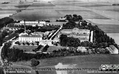 Flygfoto över Vipeholom Sjukhus från före mitten på 1950-talet
Från kurator Kerstin Löfströms (1928-1992) bildsamling från Vipeholms sjukhus i Lund, 1970 - 1980-talen och deponerad 2015-07-15 hos Sydsvenska Medicinhistoriska Sällskapet av dottern Ingrid Löfström i Lund.
Flygfoto över Vipeholom Sjukhus, taget mot öster. Motorvägen förbi sjukhuset är ännu inte byggd, dvs bilden är tagen före mitten av 1950-teaet  På fälten öster om sjukhuset byggdes stadsdelen Mårtens Fälad 1964 och 1965. På fälten nordöst om sjukhuset (på andra sidan Hardebergaspåret) byggdes Östra Torn ca 1970.
Nyckelord: Mentalsjukhus;Psykiatrisk;Klinik;Vårdhem;Vipeholmsanstalten