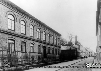 Patologiska Institutionen i Lund i början på 1900-talet
Patologicum från år 1887. Tillbyggd med en våning år 1923. Foto före tillbyggnaden. Man ser också portvaktshuset, ekonomibyggnaden och det förlängda kurhuset. Publicerad i Flaum 1968, sid. 167. Originalfoto, monterat
Nyckelord: Kapsel 17;Lund;Lasarett;Paradisgatan;Patologisk,Kliniken