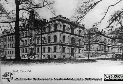 Ögonkliniken i Lund 1903
Ögonkliniken från år 1884 (i mitten) kirurgkliniken från år 1867-68 (till höger) och invärteskliniken, senare lungkliniken, från år 1850 (till vänster). I ögonklinikens källarvåning fanns lasarettets första egna köksinrättning, i första våningen, kontorslokaler. Uppe på trappan står sysslomannen P. Lundborg. Foto 1903 av Lina Johns eftr (Per Bagge). Foto: Lunds universitetsbibliotek.
Nyckelord: Kapsel 17;Lund;Lasarett;Södra;Lasarettsområde;Område;Vykort;Ögon,Kliniken;Oftalmologisk;Oftalmiatrisk