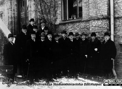 Kanske sjukhusdirektionen i Lund nära 1920
Foto vid entrétrappan till gamla ögonkliniken på södra lasarettsområdet. På trappan förmodligen Gustaf Petrén (längst till vänster på ett av trappstegen, i glasögon), eller kanske hans bror Karl. Nr 4 från höger kan vara Kjell-Otto af Klercker, pediatrikprofessor eller Elis Essen-Möller. Nr 6 är förmdligen Einar Sjövall, patologen.Möjligen kan den skäggige t hö om Petrén vara Viktor Odenius.
Ögonklinikens byggnad hyste i början också lasarettskontor och direktionsrum. Det senare flyttades någon gång efter 1918 till det s.k. portvaktshuset vid Allhelgona Kyrkogata. Bilden är rimligen tagen i samband med något sammanträde med styrande herrar i sjukhusdirektion eller landsting nära 1920.
Nyckelord: 1920-talet;Lasarettet;Lund,Universitetssjukhuset;Administration;Direktion