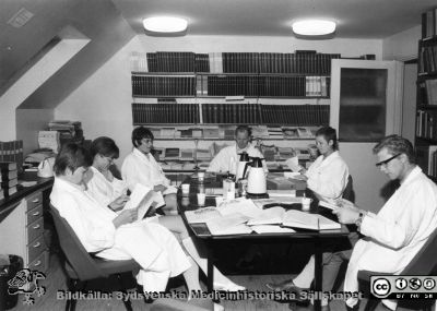  I biblioteket på översta våningen på Hudkliniken I
Ur yrkesdermatologen Sigfrid Fregerts bildsamling från hud- och könskliniken i Lund och från yrkesdermatologiska avdelningen i Lund. I biblioteket på översta våningen på Hudkliniken I. Docent Sigfrid Fregert vid bortre bordsänden. Hudäkaren Arnar Torgeirsson (Fregerts doktorand; islänning) längst till höger. Foto troligast omkring 1970. Från originalfoto.
Nyckelord: Lasarettet;Lund;Universitetssjukhuset;USiL;Hud- och könsklinik;Hud;Klinik;Dermatologisk;Venerologisk;Yrkesdermatologisk;Avdelning