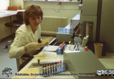 Avdelningen för klinisk kemi i Lund.
Från Boel Ohlsson 2016, Klin.kem. lab.  Lund, foto nära 1984. Annette D Wahlgren vid automatiska multi-analysapparaten Greiner GSA II
Nyckelord: Laboratorium;Lasarettet;Lund;Universitetssjukhuset;USiL;Klinisk;Kliniskt;Kemiska;Avdelningen