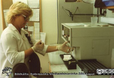 Avdelningen för klinisk kemi i Lund. Marie-Louise Nilsson vid en analysautomat.
Från Boel Ohlsson 2016, Klin.kem. lab.  Lund, tidigt 1990-tal. 	Marie-Louise Nilsson vid en analysautomat.
Nyckelord: Lasarettet;Lund;Universitetssjukhuset;USiL;Klinisk;Kliniskt;Kemiska;Avdelningen