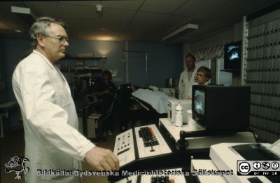 Docent Erik Lindstedt vid "Stenkrossen" i Lund,
"Stenkrossen" i Lund var en maskin (litotriptor) för att med ultraljud slå sönder fr. a. njurstenar, liptotripsi. En patient ligger i maskinen i bildens bortre del, uppenbarligen sövd. Sjuksköterskan Eva Ljunggren ses till höger i bilden. Hon var avdelningsföreståndare på urologiska klinikens mottagning. Foto Lasarettsfotograferna.
Nyckelord: Urologisk;Klinik;Universitetssjukhuset i Lund;Litotripsi