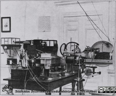 Prototypversion av Thunbergs barospirator
Prototypversion av Thunbergs barospirator. Försöksuppställning med registrering av andningsrörelser (pneumograf runt bröstkorgen), syreförbrukning (med Krogh-spirometer) och EKG (med stränggalvanometer). Det framgår inte hur dessa uppkopplingar gjordes när försökspersonen var inne i barospiratorn. Foto rimligen på 1920-talet. Bildkälla UB Lund 2020, H. Westlings arkiv.
Nyckelord: Respirator;Barospirator;Medicinsk teknik;Fysiologisk institution;Medicinska fakulteten;Universitetet i Lund