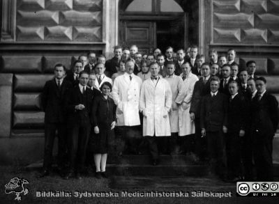 1928 års histologikurs i Lund
Fotoalbum märkt Histologikursen anno 1928. Hela kursen står tillsammans med lärarna samlade på anatomiska institutionens entrétrappa. Kursledaren, professor Torsten Hellman, står som nr 2 från vänster av lärarna som är klädda i ljusa laboratorierockar till skillnad från de manliga studenterna som bär mörka kläder. Bilden är in inte namnsatt. Detta album innehåller bilder från dåvarande histologiska avdelningen på anatomiska institutionen i Lund på Biskopsgatan 7. Det  skapades liksom de övriga i serien av kursdeltagarna och tillägnades kursledaren, professor Torsten Hellman, som uppskattning av hans lärargärning. 
Bildkälla Stiftelsen Locus Medicus Lundensis 250317.
Nyckelord: Locus Medicus Lundensis;Medicinska fakulteten i Lund;Histologiska avdelningen;Medicinska fakulteten i Lund;Sydsvenska Medicinhistoriska Sällskapet;Anatomiska Institutionen;Studenter;Lärare