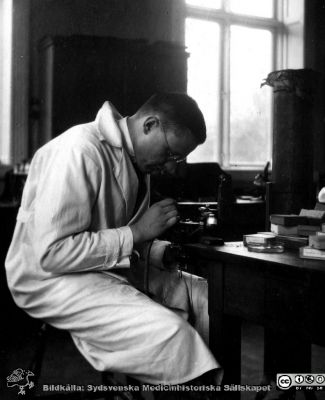 1928 års kurs i histologi i Lund
Fotoalbum märkt Histologikursen anno 1928. 
Detta album innehåller bilder från dåvarande histologiska avdelningen på anatomiska institutionen i Lund på Biskopsgatan 7. Liksom de övriga i serien skapades det av kursdeltagarna och tillägnades kursledaren, professor Torsten Hellman, som uppskattning av hans lärargärning. Bildtext  "Dahlins starka sida". Amanuensen Henry Dahlin vid mikroskoöet. 
Bildkälla Stiftelsen Locus Medicus Lundensis 250317.
Nyckelord: Locus Medicus Lundensis;Medicinska fakulteten i Lund;Histologiska avdelningen;Sydsvenska Medicinhistoriska Sällskapet;SMHS;Anatomiska Institutionen;Studenter;Lärare