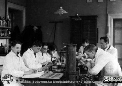 1928 års kurs i histologi i Lund
Fotoalbum märkt Histologikursen anno 1928. 
Detta album innehåller bilder från dåvarande histologiska avdelningen på anatomiska institutionen i Lund på Biskopsgatan 7. Liksom de övriga i serien skapades det av kursdeltagarna och tillägnades kursledaren professor Torsten Hellman som uppskattning av hans lärargärning. Bildtext nedanför: "Göran Gerner, Ivan Gotthard, Sjövall. Studenterna och amanuens Sjövall producerar troligast preparat på objektglas för mikroskopi. Apparaten till höger närmast kameran är en frysmikrotom med tillhörande gastub för frysning med koldioxid.
Bildkälla Stiftelsen Locus Medicus Lundensis 250317.
