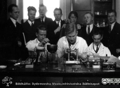 1928 års kurs i histologi i Lund
Fotoalbum märkt Histologikursen anno 1928. 
Detta album innehåller bilder från dåvarande histologiska avdelningen på anatomiska institutionen i Lund på Biskopsgatan 7. Liksom de övriga i serien skapades det av kursdeltagarna och tillägnades kursledaren, professor Torsten Hellman som uppskattning av hans lärargärning. Bildtext ovanför "Göran Gerner". Nedanför: "Nystrand, Sjövall, Christiansson". Kanske tre amanuenser som visar ttillverkning av preparat på objektglas för mikroskopiering. 
Bildkälla Stiftelsen Locus Medicus Lundensis 250317.
Nyckelord: Locus Medicus Lundensis;Medicinska fakulteten i Lund;Histologiska avdelningen;Sydsvenska Medicinhistoriska Sällskapet;SMHS;Anatomiska Institutionen;Studenter;Lärare