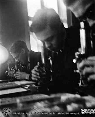 1928 års kurs i histologi i Lund
Fotoalbum märkt Histologikursen anno 1928. 
Detta album innehåller bilder från dåvarande histologiska avdelningen på anatomiska institutionen i Lund på Biskopsgatan 7. Liksom de övriga i serien skapades det av kursdeltagarna och tillägnades kursledaren professor Torsten Hellman som uppskattning av hans lärargärning. Bildtext  "Hugo Andersson, Axel Varenius, Göran Nilsson". Studenter vid kursmikroskop.
Bildkälla Stiftelsen Locus Medicus Lundensis 250317.
Nyckelord: Locus Medicus Lundensis;Medicinska fakulteten i Lund;Histologiska avdelningen;Sydsvenska Medicinhistoriska Sällskapet;SMHS;Anatomiska Institutionen;Studenter