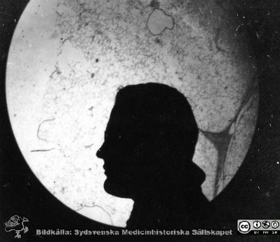 1928 års kurs i histologi i Lund
Fotoalbum märkt Histologikursen anno 1928. 
Detta album innehåller bilder från dåvarande histologiska avdelningen på anatomiska institutionen i Lund på Biskopsgatan 7. Liksom de övriga i serien skapades det av kursdeltagarna och tillägnades kursledaren professor Torsten Hellman som uppskattning av hans lärargärning. Bildtext  "Dahlin". Silhuett av amanuensen Henry Dahlin framför en projicerad mikroskopbild (kanske en bit bindväv).
Bildkälla Stiftelsen Locus Medicus Lundensis 250317.
Nyckelord: Locus Medicus Lundensis;Medicinska fakulteten i Lund;Histologiska avdelningen;Sydsvenska Medicinhistoriska Sällskapet;SMHS;Anatomiska Institutionen;Studenter;Lärare