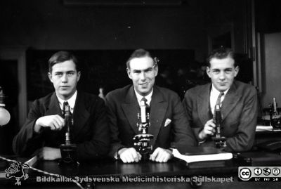 Fotoalbum från histologikursen 1931
Fotoalbum från histologikursen 1931. Bildtext "Lindstam, Olsson, Thulin".  Tre medicine studerande i mikroskoperingssalen.  Eleven i mitten bör vara Olle Olsson (1911 - 1999), senare professor i röntgenologi i Lund). 
Bildkälla Stiftelsen Locus Medicus Lundensis 250317. Sydsvenska Medicinhistoriska Sällskapet / SMHS. Fotograf okänd.
Nyckelord: Histologiska avdelningen;Anatomiska Institutionen;Locus Medicus Lundensis;Medicinska fakulteten i Lund;Medicine studerande;Elever