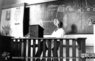Fotoalbum från histologikursen 1931
Fotoalbum från histologikursen 1931. Bildtext "Den lymfatiska vävnaden under prövning". Amanuens Gösta Glimstedt vid katetern i stora föreläsningssalen på anatomiska institutionen i Lund. 
Bildkälla Stiftelsen Locus Medicus Lundensis 250317. Sydsvenska Medicinhistoriska Sällskapet / SMHS. Fotograf okänd.
Nyckelord: Medicine studerande;Histologiska avdelningen;Anatomiska Institutionen;Mikroskoperingssal;Medicinska fakulteten i Lund;Locus Medicus Lundensis;Universitetet i Lund