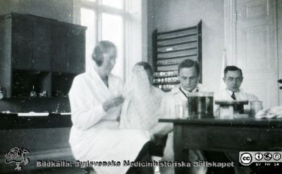 Fotoalbum  "Kursen i histologi H T 1932
Fotoalbum  "Kursen i histologi H T 1932".  Bildtext "Kökspersonalen i arbete". Oklart vad för slags avancerad tillagningskonst som visas upp, histologiskt preparat eller brygd för fest med kurskamrater.  Bilden kan också ses som en fortsättning på bildserien "Sällskapsliv". Troligen medicinare under studier på histologiska avdelningens mkroskoperingssal på anatomiska institutionen i Lund. 
Bildkälla stiftelsen Locus Medicus Lundensis och Sydsvenska Medicinhistoriska Sällskapet / SMHS. Fotograf okänd.
Nyckelord: Universitetet i Lund;Locus Medicus Lundensis;Anatomiska Institutionen;Histologiska avdelningen;Sydsvenska Medicinhistoriska Sällskapet;SMHS;Medicine studerande