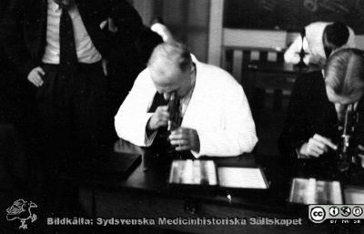 Fotoalbum  tillägnat Professor Torsten Hellman av lärjungarna 1935. Bildtext saknas. Professor Hellman hjälper studenterna i mikroskop. De är medicine studerande på avdelningen för histologi på anatomiska institutionen i Lund. 
Bildkälla stiftelsen Locus Medicus Lundensis och Sydsvenska Medicinhistoriska Sällskapet / SMHS. Fotograf okänd.
Nyckelord: Histologiska avdelningen;Anatomiska Institutionen;Sydsvenska Medicinhistoriska Sällskapet;Medicinska fakulteten i Lund;Locus Medicus Lundensis;Medicine studerande;Lunds universitet