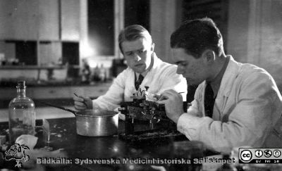 Fotoalbum  tillägnat Professor Torsten Hellman av lärjungarna 1935. Bildtext: Laborationer. Preparaten snittas." saknas. Två unga medicinare i kurslaboratoriet. De är medicine studerande på avdelningen för histologi på anatomiska institutionen i Lund. 
Bildkälla stiftelsen Locus Medicus Lundensis och Sydsvenska Medicinhistoriska Sällskapet / SMHS. Fotograf okänd.
Nyckelord: Histologiska avdelningen;Anatomiska Institutionen;Sydsvenska Medicinhistoriska Sällskapet;Medicinska fakulteten i Lund;Locus Medicus Lundensis;Medicine studerande;Lunds universitet